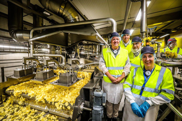 Workers standing in a plant next to chips